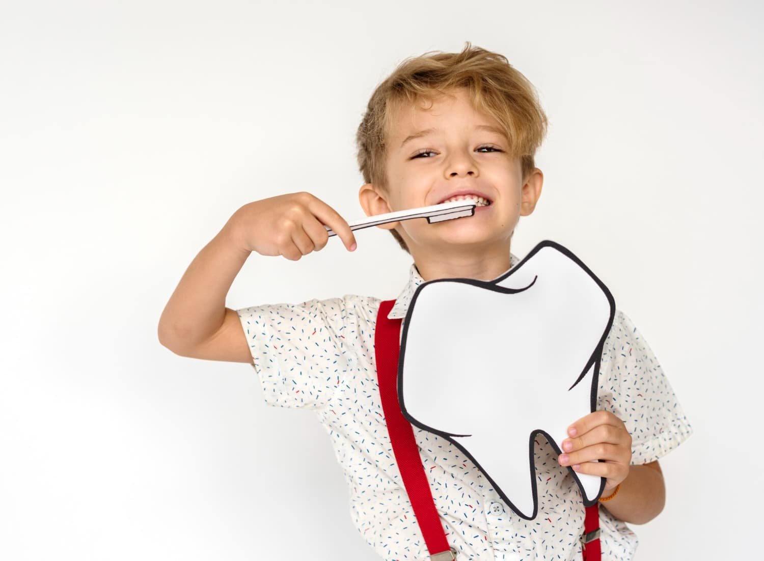 A happy child smiling while brushing his teeth, promoting good oral hygiene. 