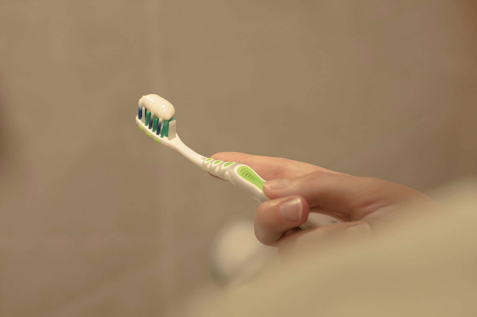 Close-up of a blue soft-bristled toothbrush next to a tube of fluoride toothpaste, ready for daily brushing.