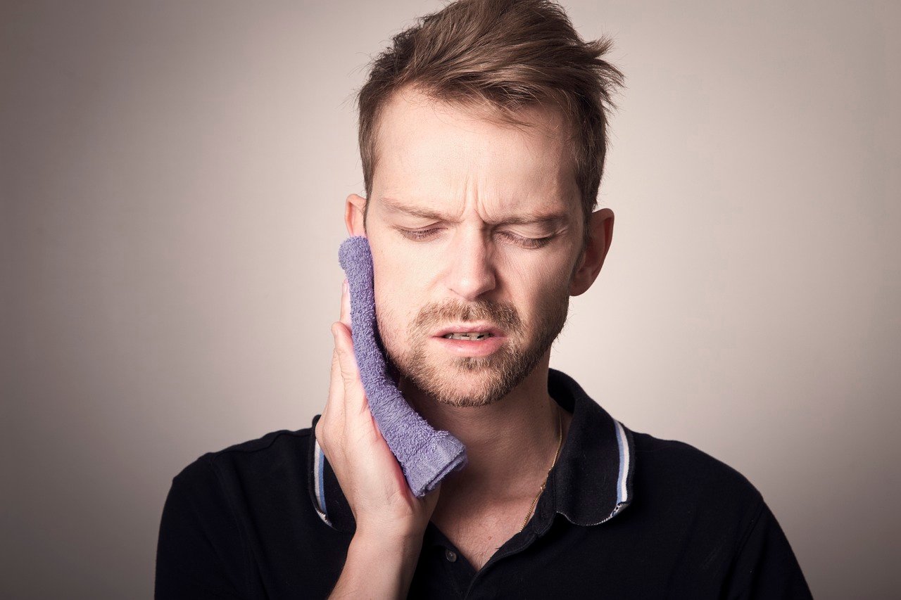 Man holding jaw in pain due to tooth cavities